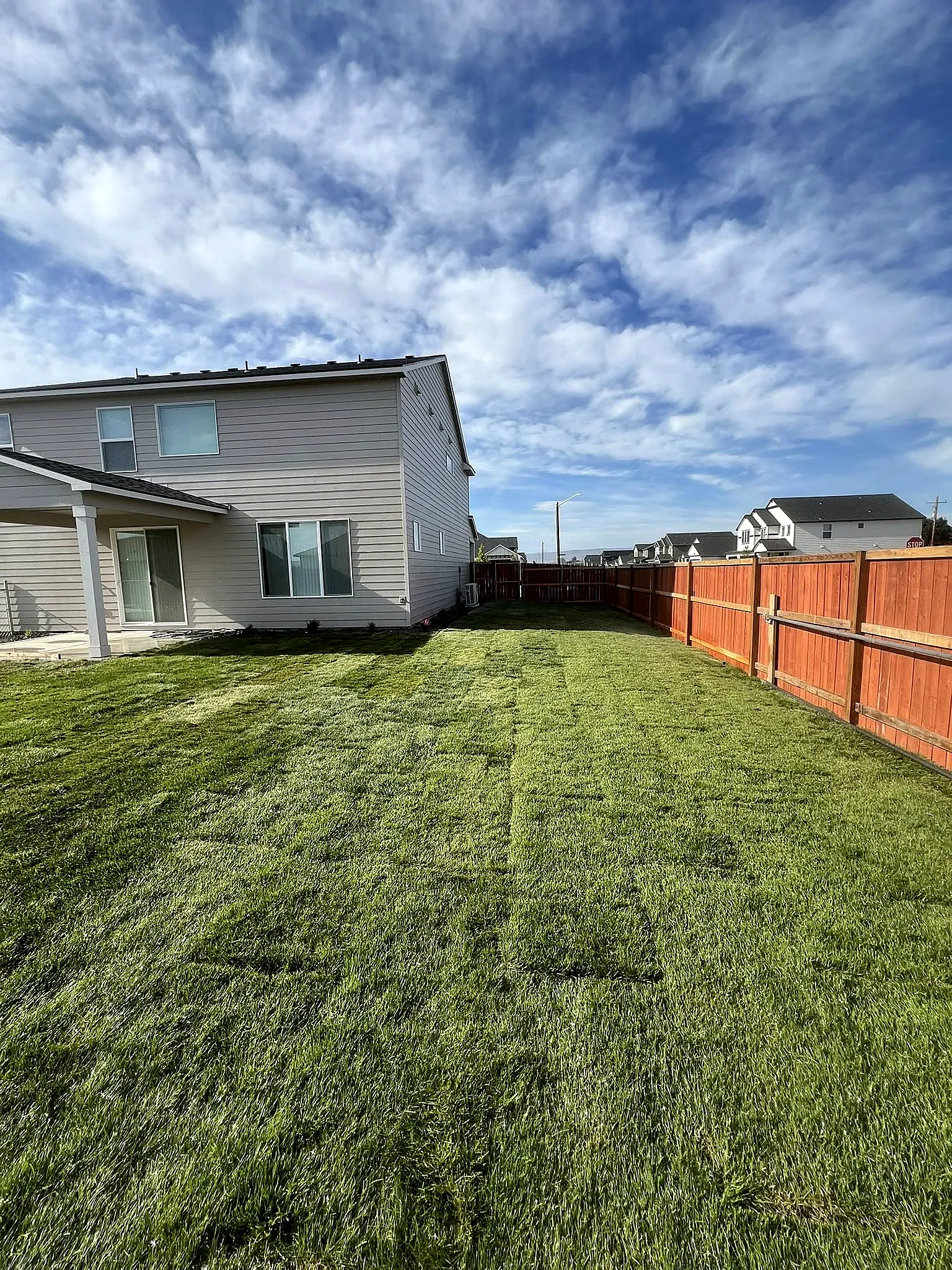 A backyard transformed with lush new sod beside a new wood privacy fence in the Lower Yakima Valley