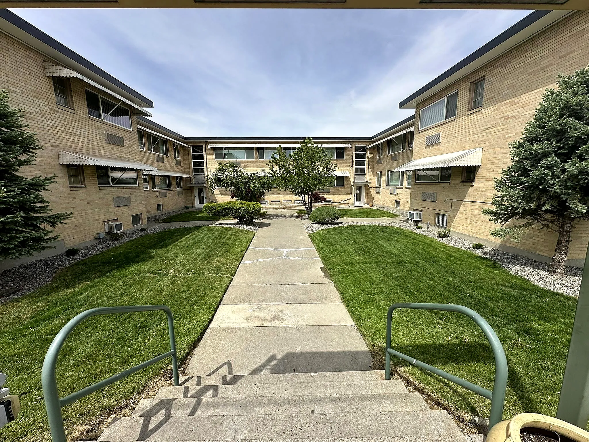 A managed multi-unit property courtyard with tidy lawns, a clean walkway, and maintained landscaping in Prosser, WA