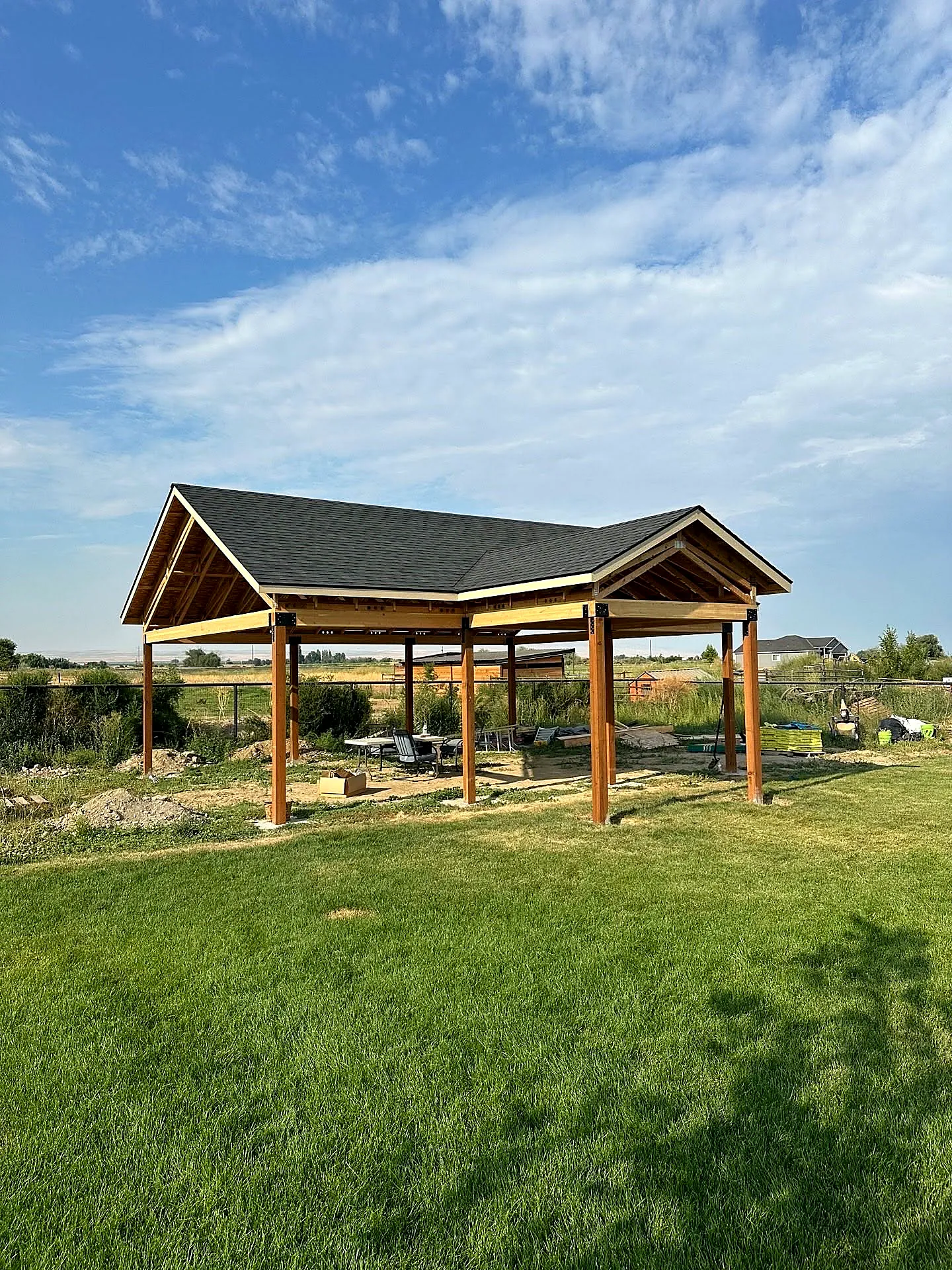A custom timber-framed backyard pavilion set on a green lawn — an outdoor-living hardscape feature by Outwest